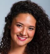 Closeup image of a woman's face with curly hair wearing makeup