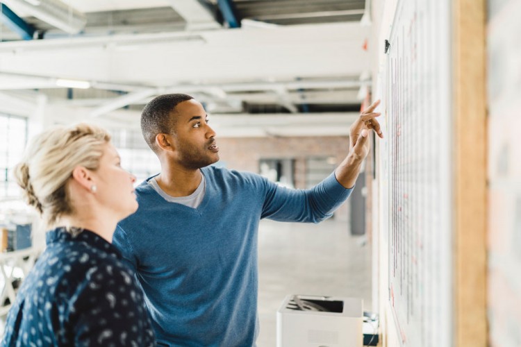 Image of two people pointing at a board