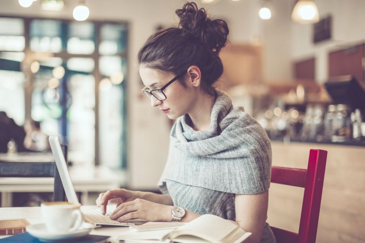 Image of woman sitting at a table doing work on her laptop