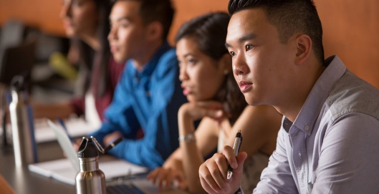 Image student sitting amongst other students paying attention in a classroom