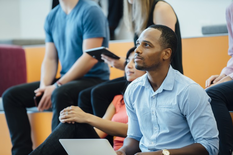 Man taking notes, watching a presentation